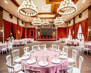 restaurant hall with small stage monitor red curtains brick walls white napoleon chairs 1 11zon